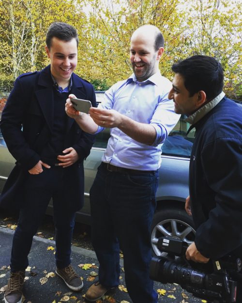 Matthew Timmons-Brown and Eben Upton standing in a car park looking at a smartphone