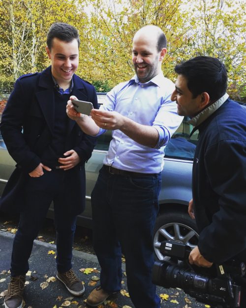 Matthew Timmons-Brown Matthew Timmons-Brown and Eben Upton standing in a car park looking at a smartphone