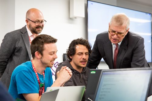 Prince Andrew and three other men watching a computer screen