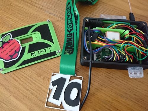 The brick, a small plastic box full of coloured jumper leads and other electronics; the lid of the box; and a medal consisting of the number 10 in large plastic characters on a green ribbon
