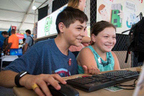 A smiling boy and girl looking at a computer screen
