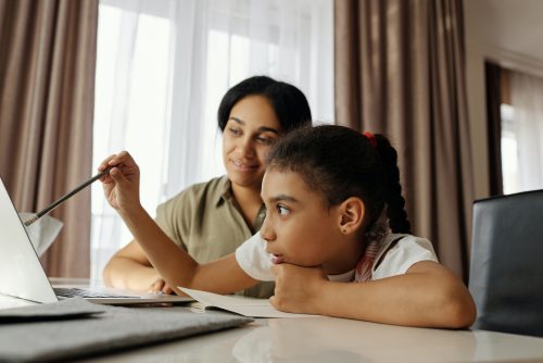 A girl and mother doing a homeschooling lesson at a laptop