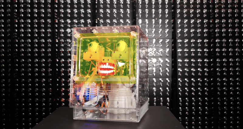 furby facial recognition robot in a clear case in front of a dark background