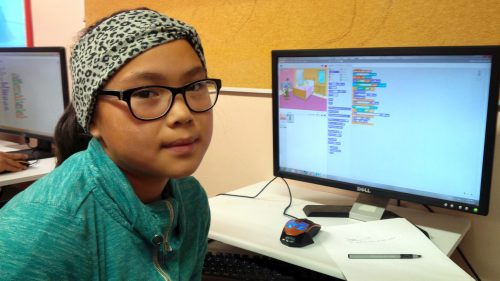 A girl with her Scratch coding project on a desktop computer.