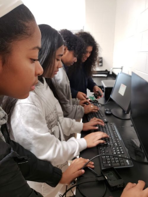 Four young women of colour code at computers