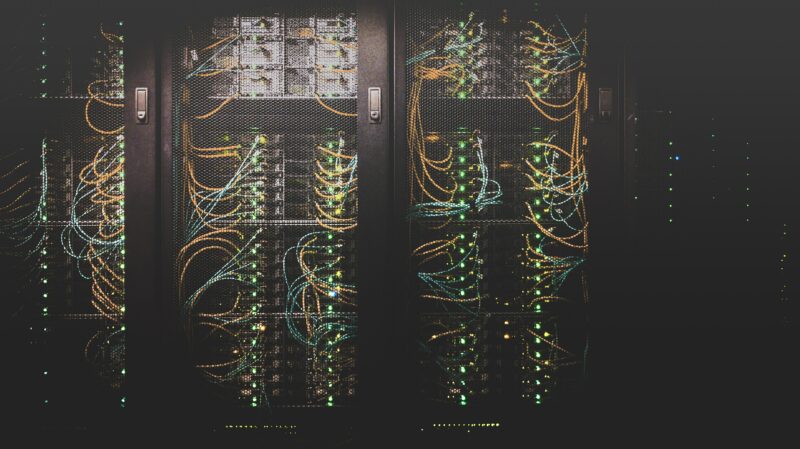 Stacks of server hardware behind metal fencing in a data centre.