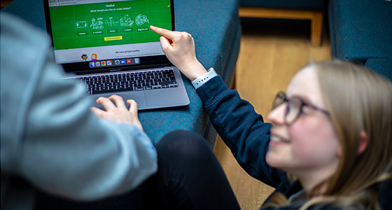 A girl points happily at a project on the Raspberry Pi Foundation's projects site.