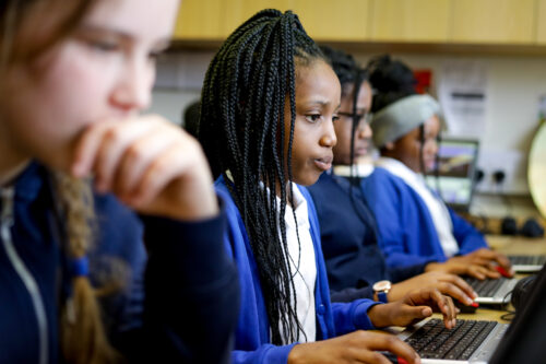 In a computer science class, two girls are concentrating on their programming task.